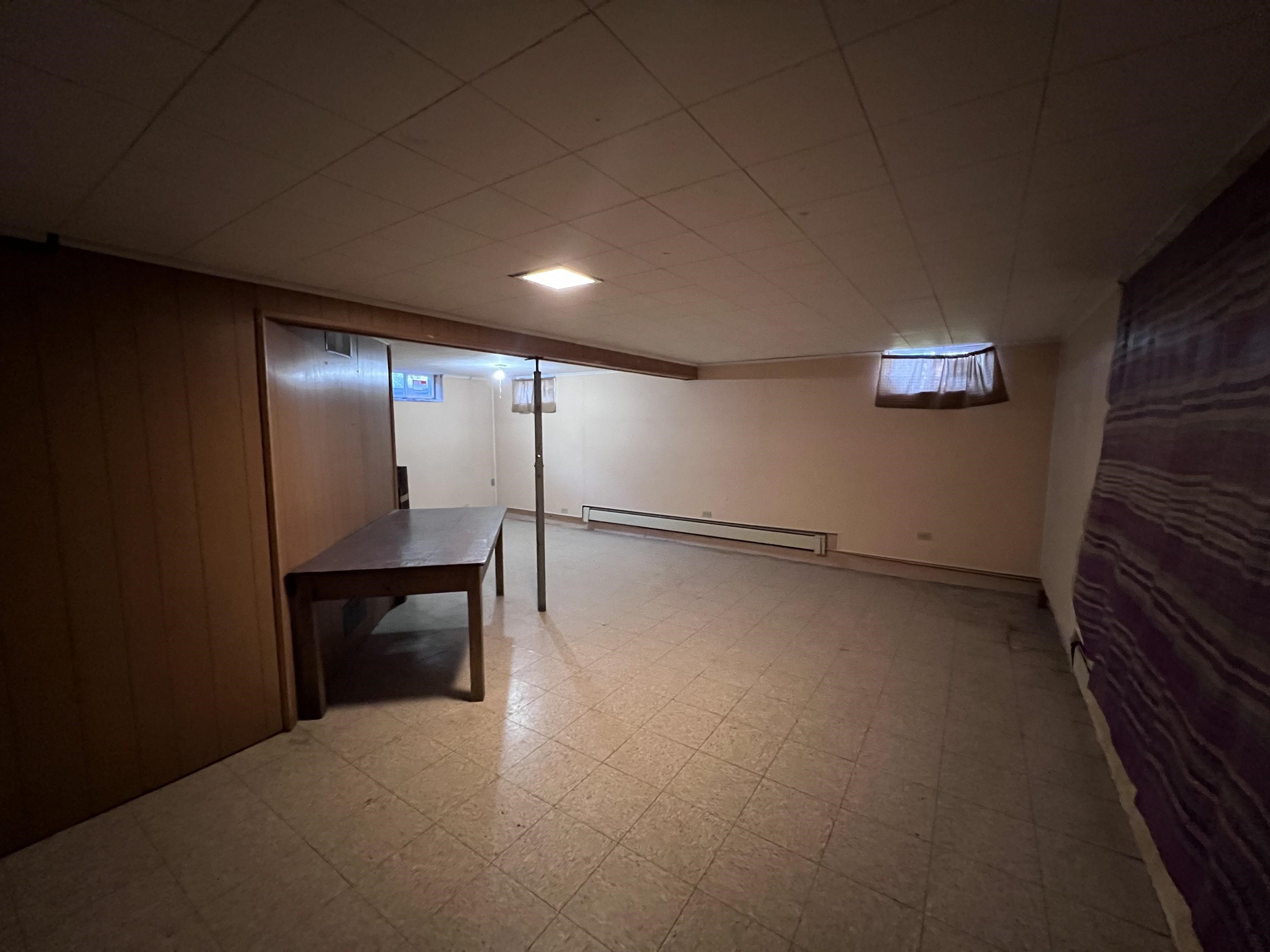 202 North 58th Street Superior, WI 54880 - Photo 17 of 30 Basement featuring light flooring, a baseboard heating unit, and wood walls
