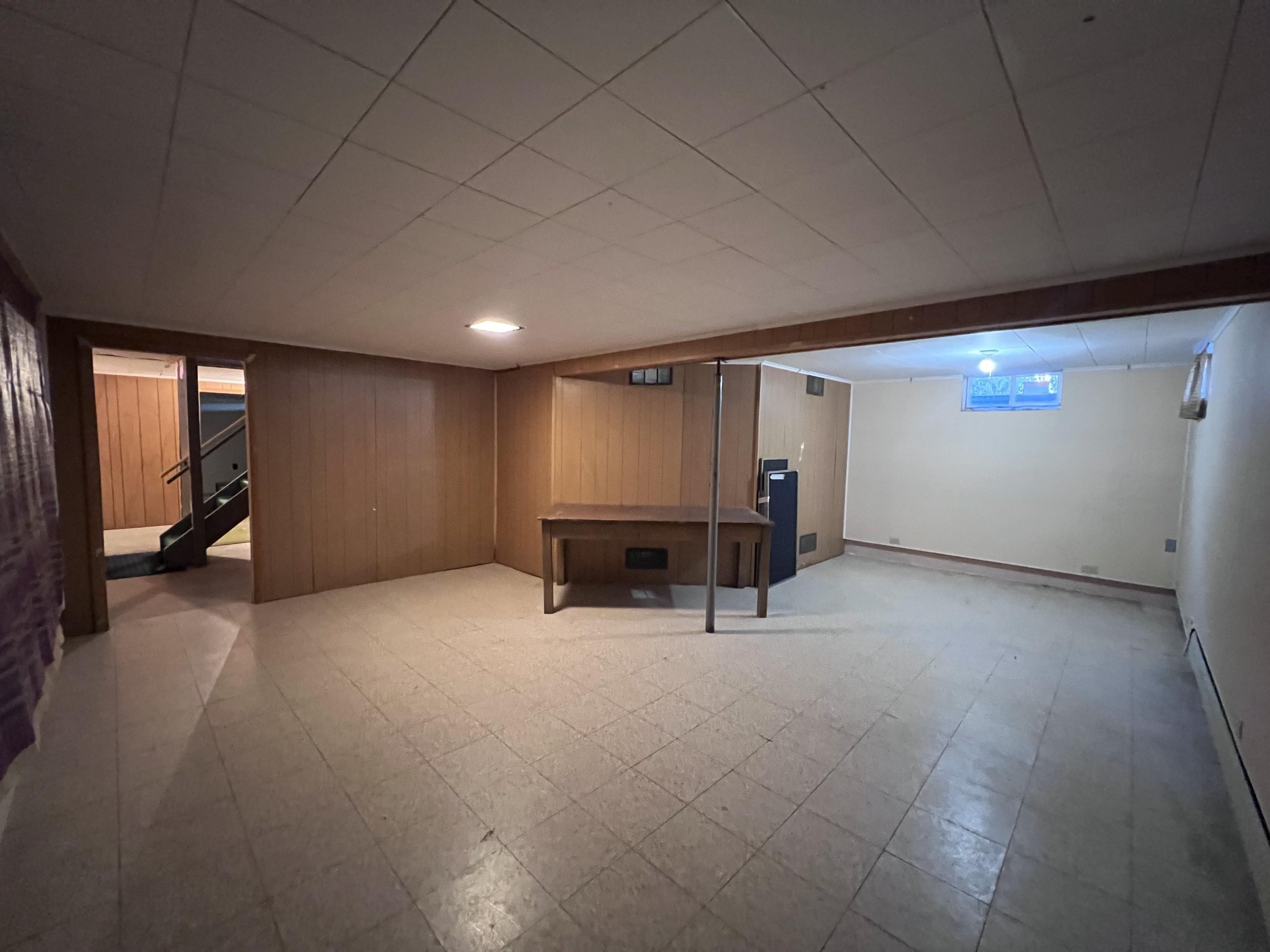 202 North 58th Street Superior, WI 54880 - Photo 18 of 30 Basement featuring light floors, a baseboard heating unit, stairway, and wood walls