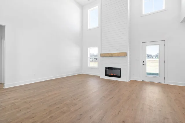 a view of an empty room with wooden floor fireplace and a window