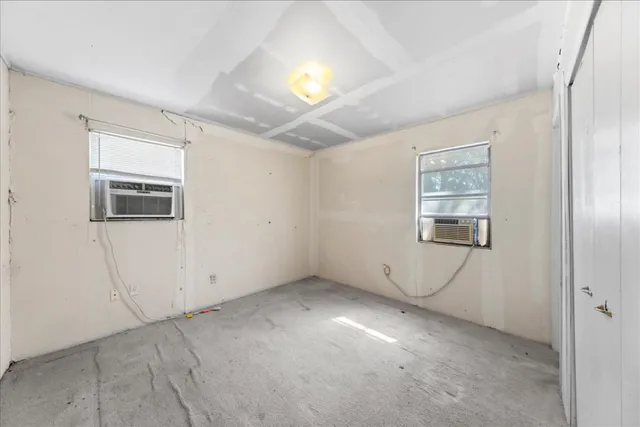 an empty room with windows and fireplace