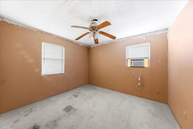 an empty room with windows and fan