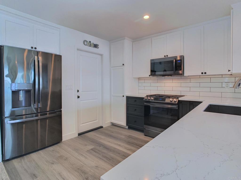 10005 3 Oaks Way Santee, CA 92071 - Photo 9 of 25 a kitchen with stainless steel appliances kitchen island granite countertop a refrigerator stove and microwave