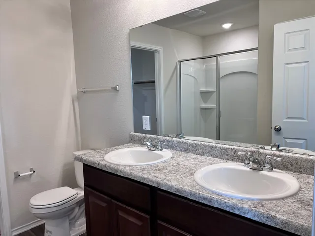 a bathroom with a double vanity sink a large mirror and shower