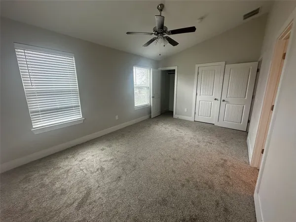 an empty room with windows and fan