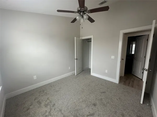 an empty room with a fan & a ceiling fan