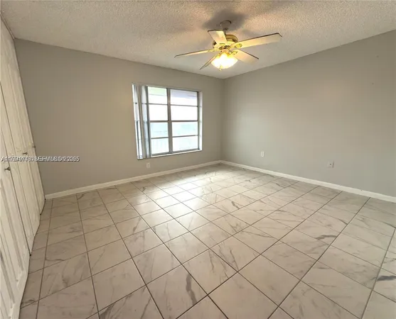 a view of an empty room and chandelier fan