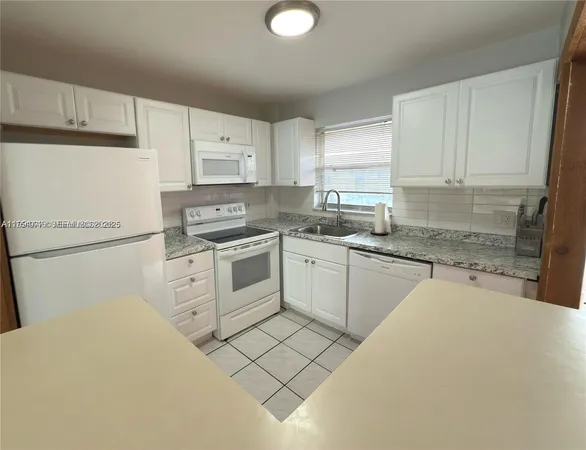 a kitchen with white cabinets appliances and a sink