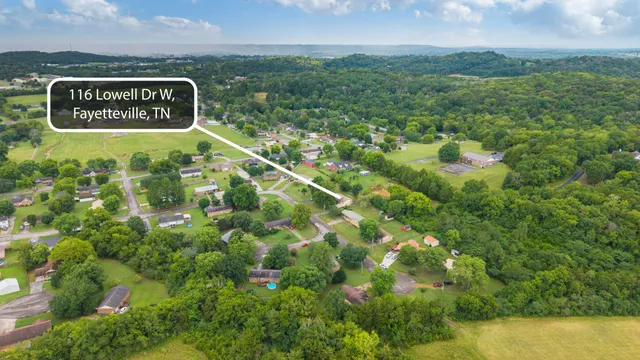 a sign of golf club on a wall under a large tree