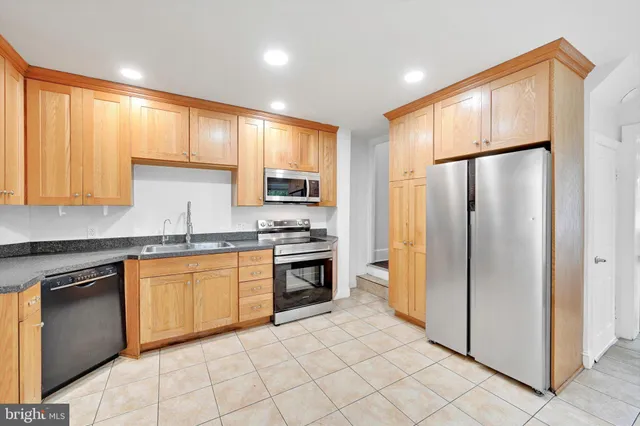 a kitchen with stainless steel appliances granite countertop a refrigerator sink and stove