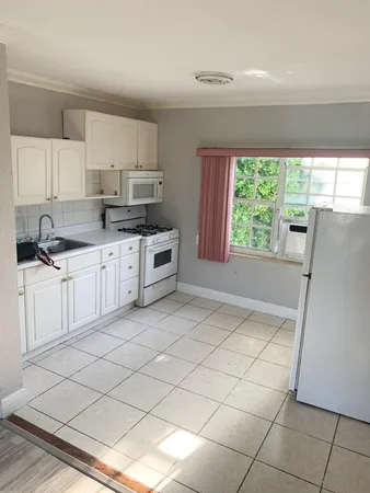 a kitchen with granite countertop a sink window and cabinets