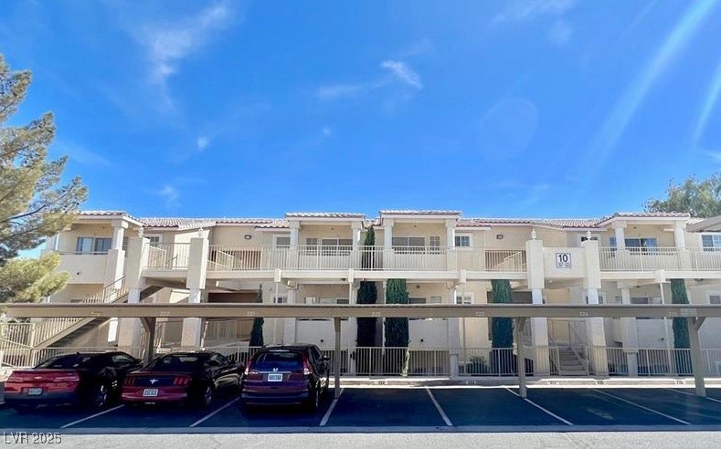 View of apartment building / complex featuring covered parking