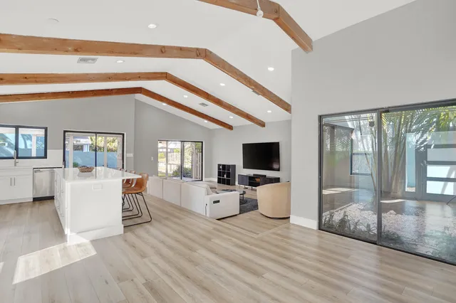 a living room with furniture a flat screen tv and large window