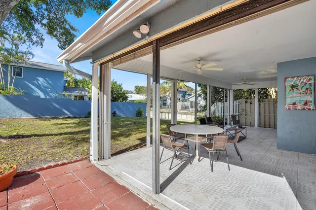 a patio with table and chairs and potted plants