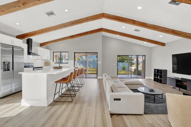 a living room with furniture a flat screen tv and a floor to ceiling window