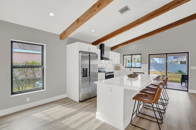 a living room with stainless steel appliances furniture a rug and a large window