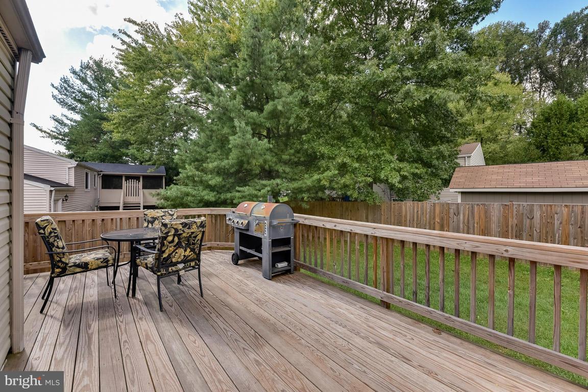 5809 Heming Avenue Springfield, VA 22151 - Photo 19 of 22 a view of a roof deck with table and chairs a barbeque with wooden floor and fence