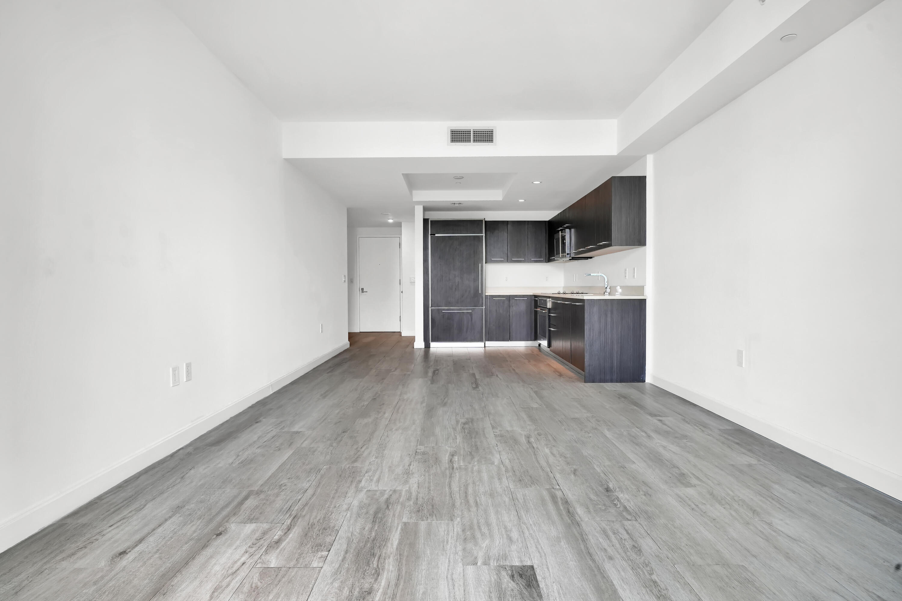 55 Southwest 9th Street, Unit 3504 Miami, FL 33130 - Photo 11 of 33 an empty room with wooden floor and kitchen view