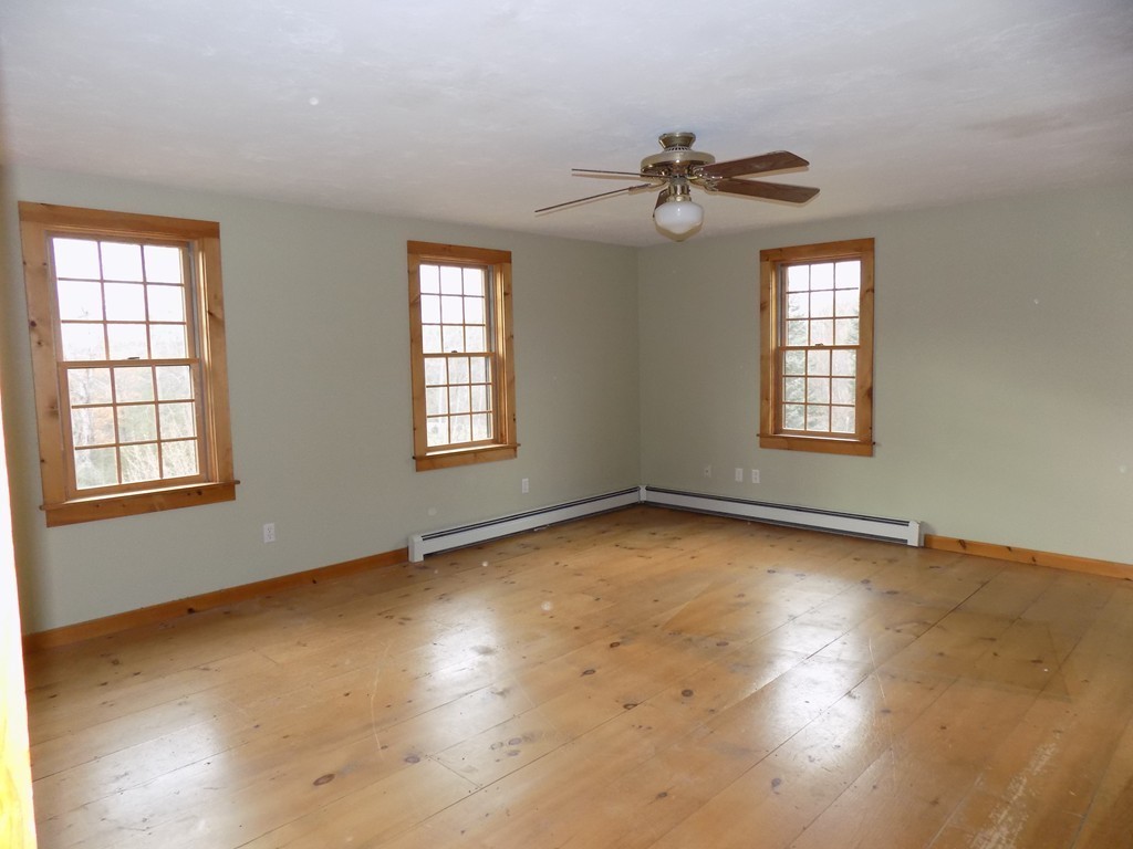 176 Crouch Road Warren, MA 01092 - Photo 9 of 19 an empty room with wooden floor chandelier fan and windows