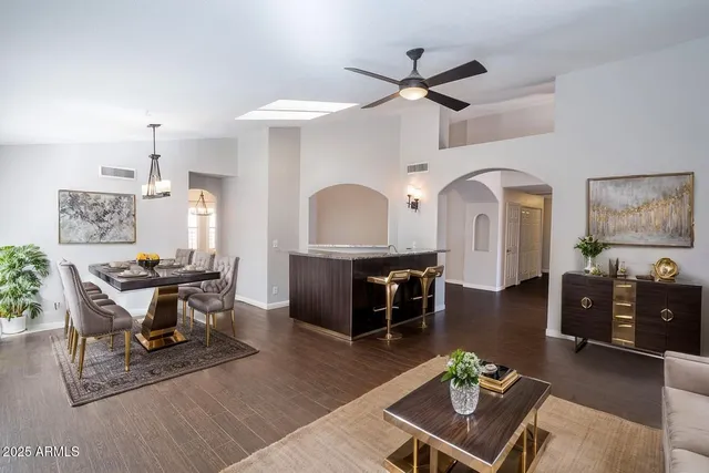 a living room with couches a dining table with kitchen view and wooden floor