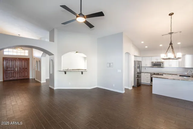 a view of a kitchen with a stove wooden cabinet a refrigerator wooden floor and a chandelier