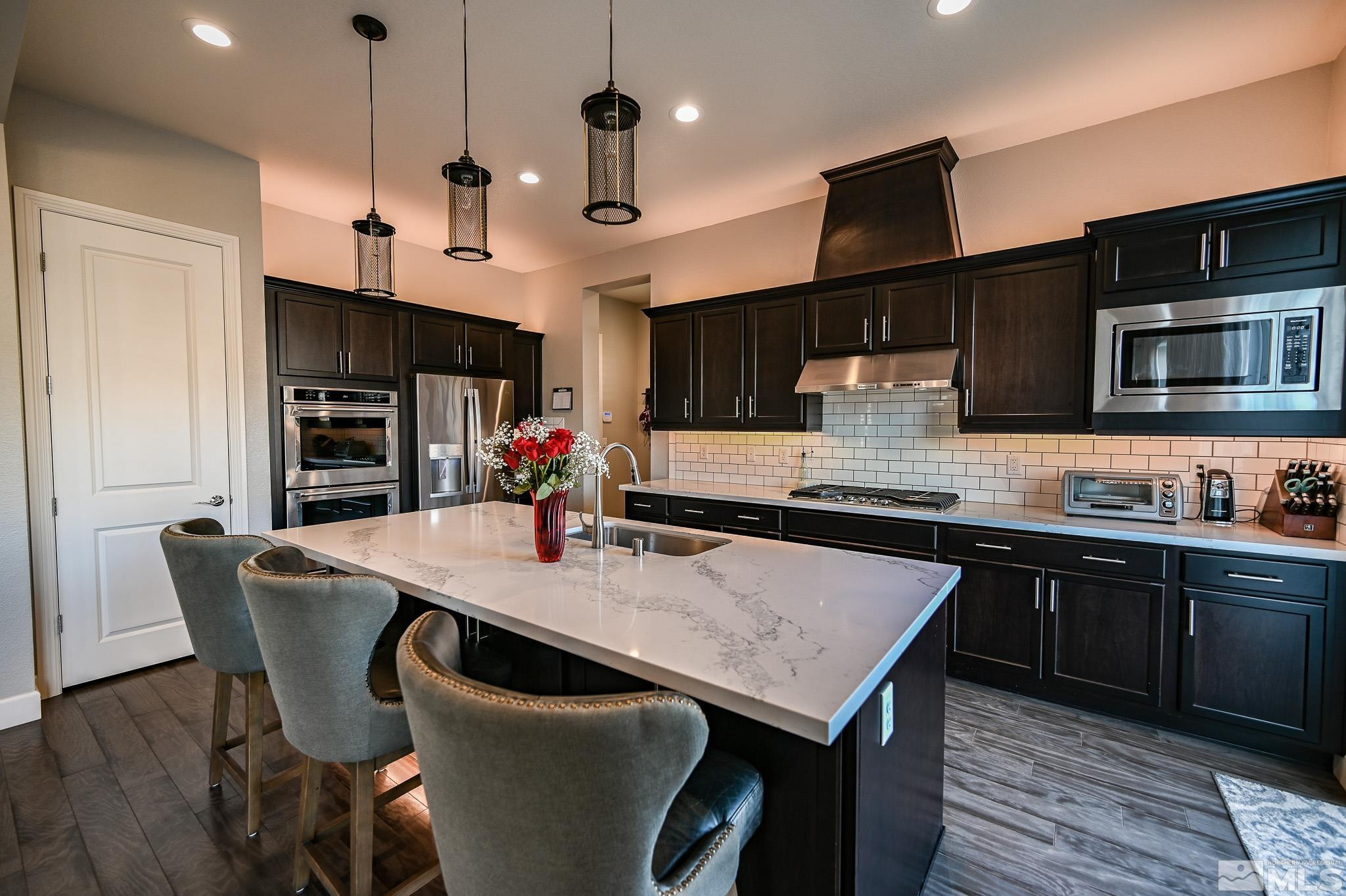 9330 Mayfair Way Reno, NV 89521 - Photo 9 of 40 a kitchen with stainless steel appliances granite countertop a kitchen island a stove a table and chairs