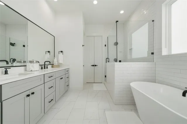 a bathroom with a double vanity sink a large mirror and a bathtub
