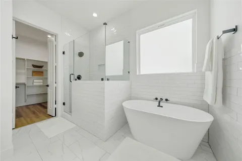 a bathroom with a white tub shower sink and mirror