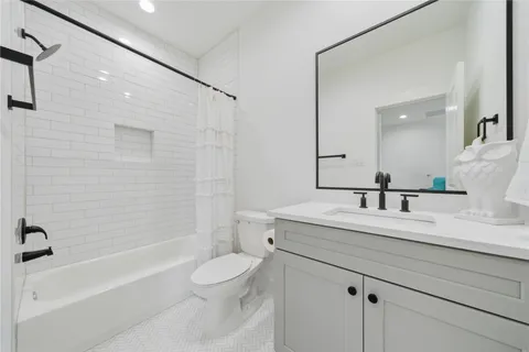 a bathroom with a granite countertop sink a toilet a mirror a bathtub and shower