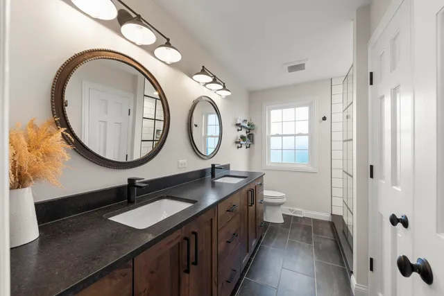 a bathroom with a granite countertop double vanity sink and a mirror