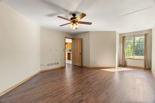 a view of a room with wooden floor and a ceiling fan