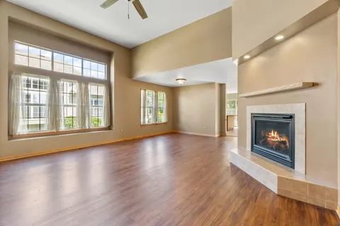 a view of an empty room with wooden floor fireplace and a window