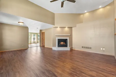 an empty room with wooden floor fireplace and windows
