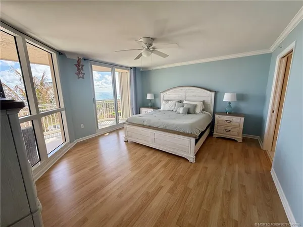 a bedroom with a bed and a large window with wooden floor