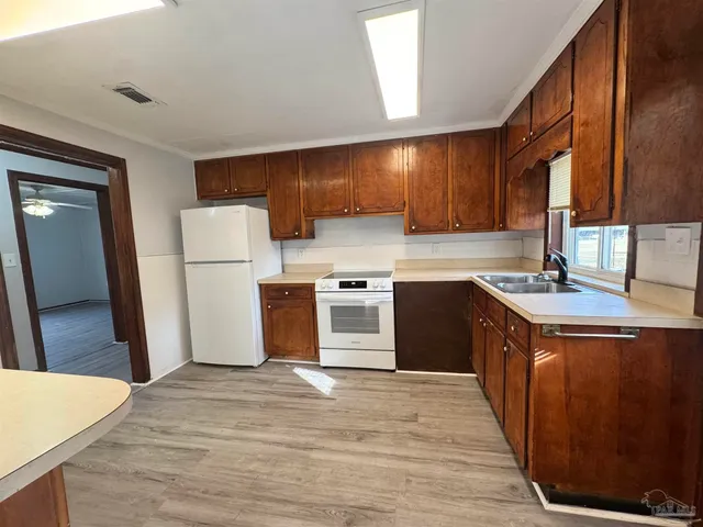 a kitchen with stainless steel appliances granite countertop a stove a sink and a refrigerator with wooden cabinets