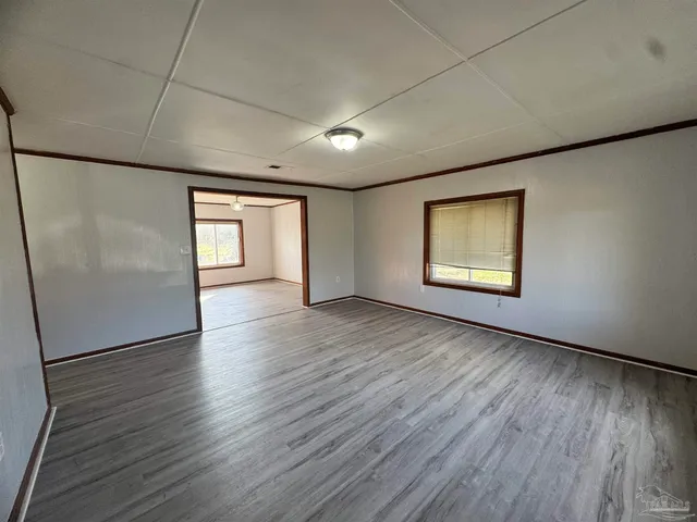 an empty room with wooden floor cabinet and windows
