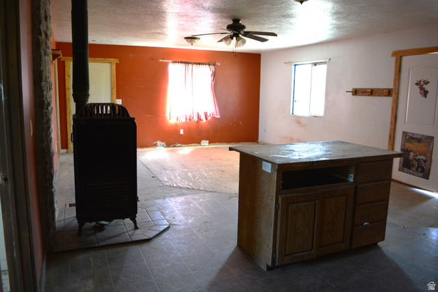 636 Cemetery Road Dingle, ID 83233 - Photo 4 of 22 Open concept room featuring a built-in wood-burning stove with a stone surround, a ceiling fan, and tile flooring