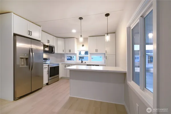 a kitchen with stainless steel appliances granite countertop a refrigerator a sink a stove and a refrigerator