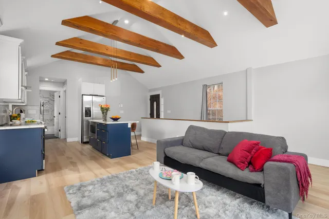 a kitchen with stainless steel appliances a stove a sink a refrigerator and white cabinets with wooden floor