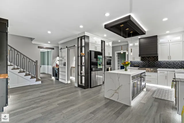 a open kitchen with stainless steel appliances granite countertop a stove top oven a refrigerator a dining table and chairs with wooden floor