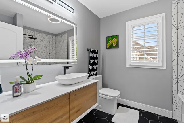 a bathroom with a granite countertop sink vanity mirror and toilet