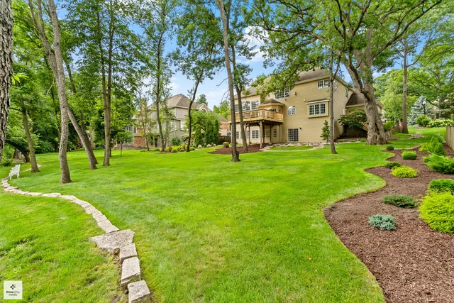 a view of a white house with a big yard and large trees