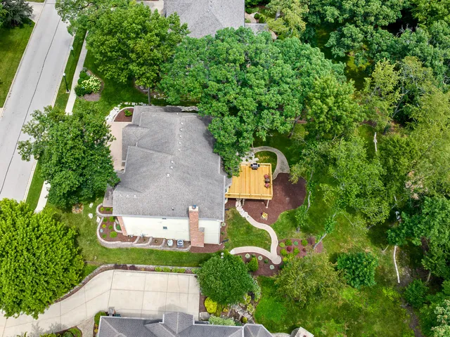 an aerial view of a house with a yard and trees all around