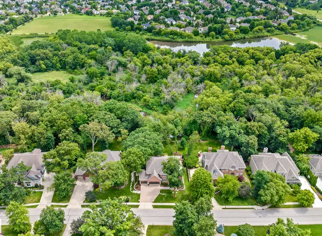 an aerial view of residential house with outdoor space and trees all around