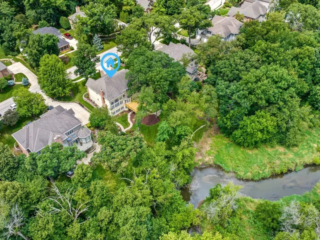 an aerial view of residential house with outdoor space and trees all around