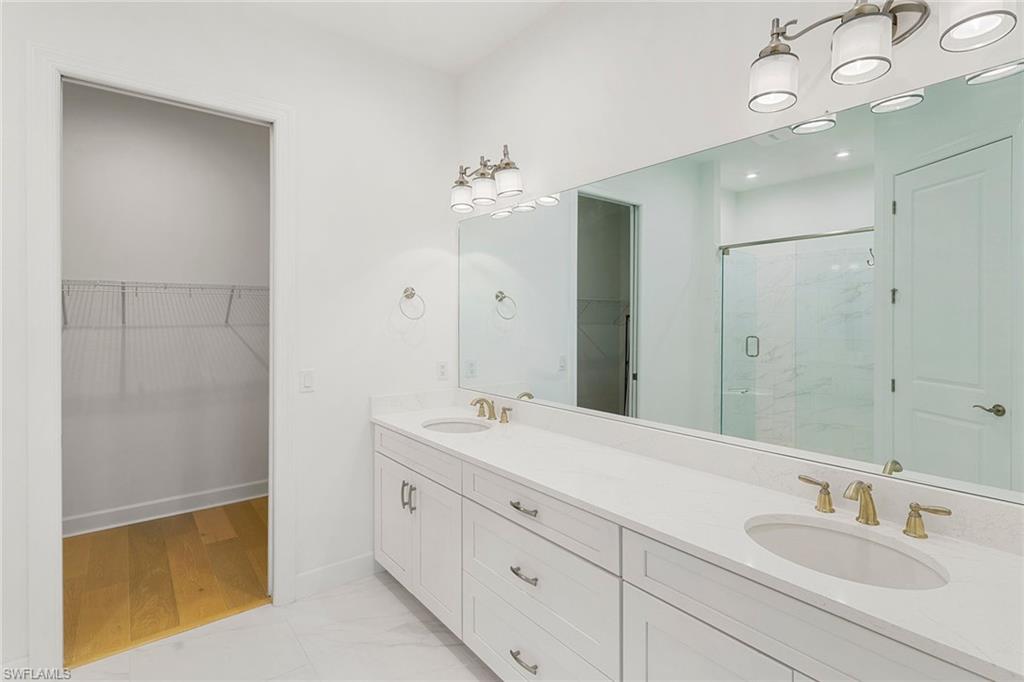 9633 Montelanico Loop, Unit 203 Naples, FL 34119 - Photo 18 of 33 a bathroom with a double vanity sink and a mirror