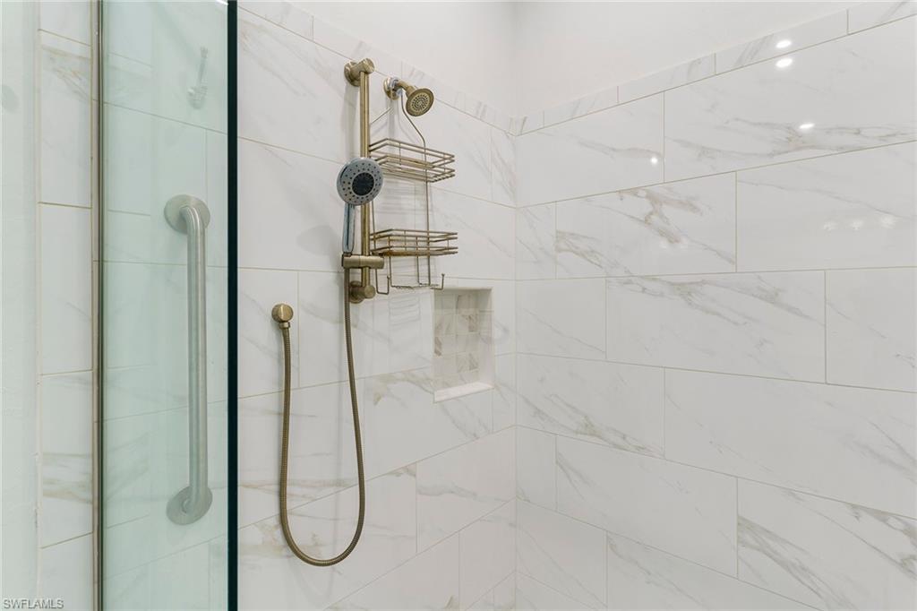 9633 Montelanico Loop, Unit 203 Naples, FL 34119 - Photo 19 of 33 a bathroom with a glass shower door