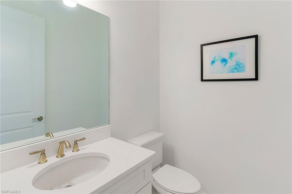 9633 Montelanico Loop, Unit 203 Naples, FL 34119 - Photo 24 of 33 a bathroom with a toilet sink and mirror