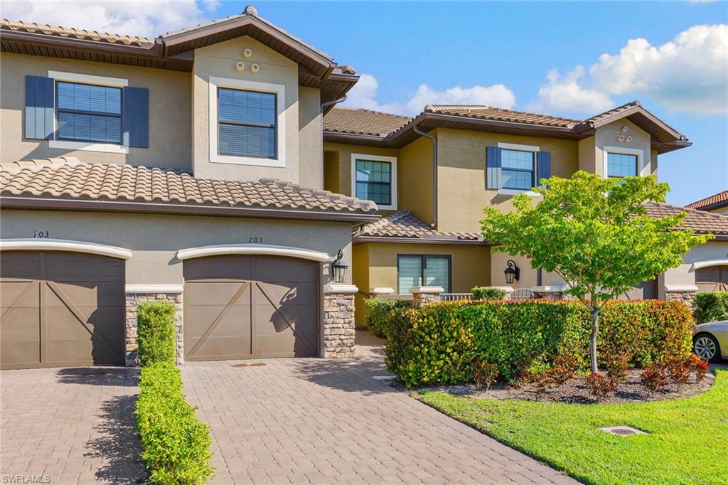 9633 Montelanico Loop, Unit 203 Naples, FL 34119 - Photo 5 of 33 a front view of a house with a garden and plants
