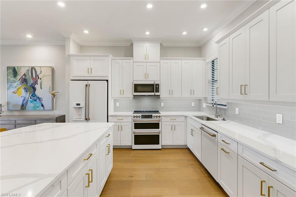9633 Montelanico Loop, Unit 203 Naples, FL 34119 - Photo 8 of 33 a large white kitchen with stainless steel appliances granite countertop a stove and a sink