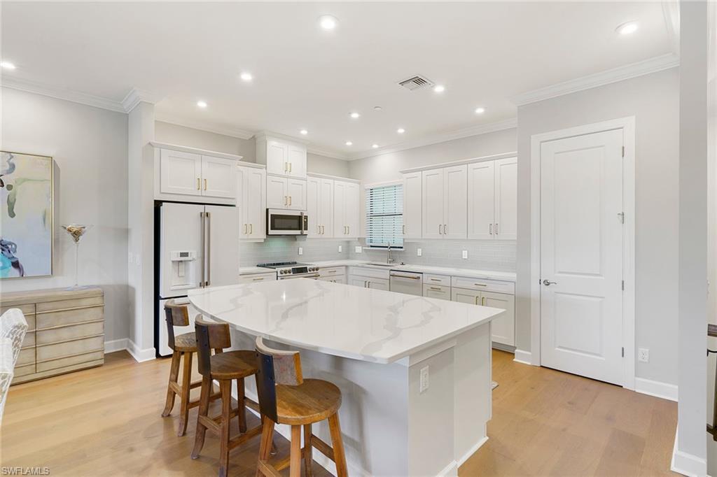 9633 Montelanico Loop, Unit 203 Naples, FL 34119 - Photo 10 of 33 a large kitchen with kitchen island white cabinets and stainless steel appliances